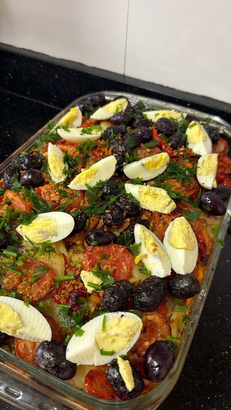 Travessa de vidro assada com tomate, ovos cozidos, azeitonas pretas e cheiro-verde